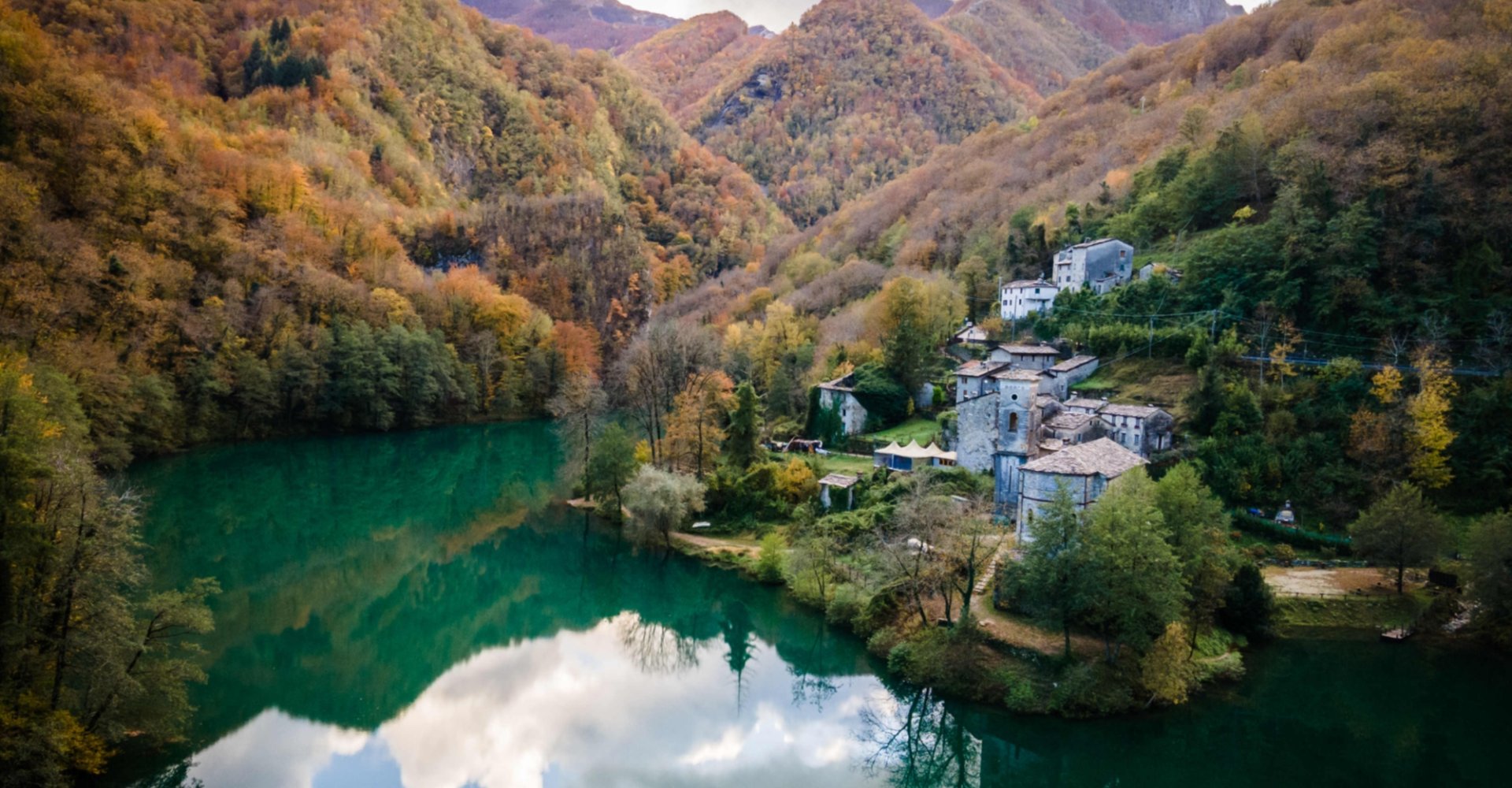 Pequeña aldea con vista a un lago y rodeada de montañas.